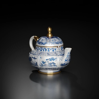 Porcelain teapot with intricate designs, elegant handle, ornate lid.
